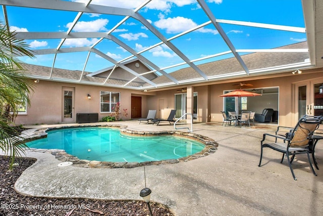 pool featuring glass enclosure, a patio area, and a ceiling fan