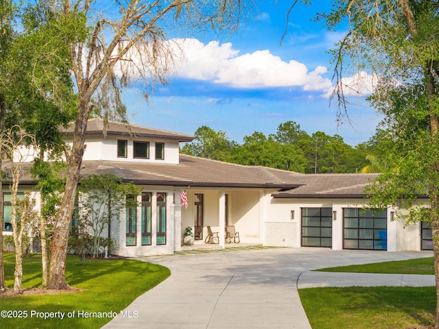 view of front facade with an attached garage, a front lawn, concrete driveway, and stucco siding