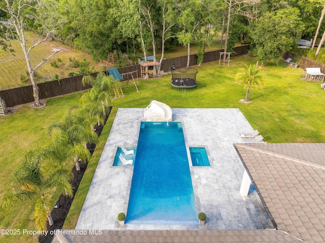 view of pool with a water slide, a fenced backyard, a yard, a trampoline, and a patio area