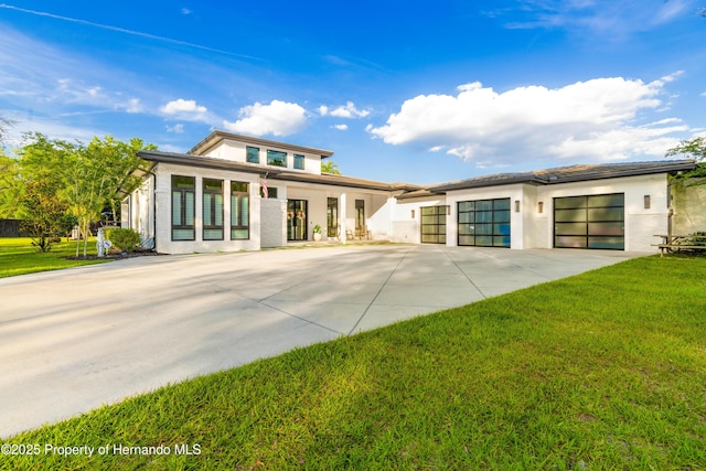 prairie-style home with a garage, driveway, a front lawn, and stucco siding