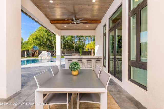 view of patio with an outdoor kitchen, a fenced backyard, outdoor wet bar, a ceiling fan, and a fenced in pool