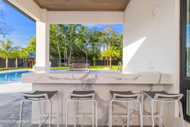 view of patio / terrace featuring outdoor wet bar, a fenced in pool, and a fenced backyard