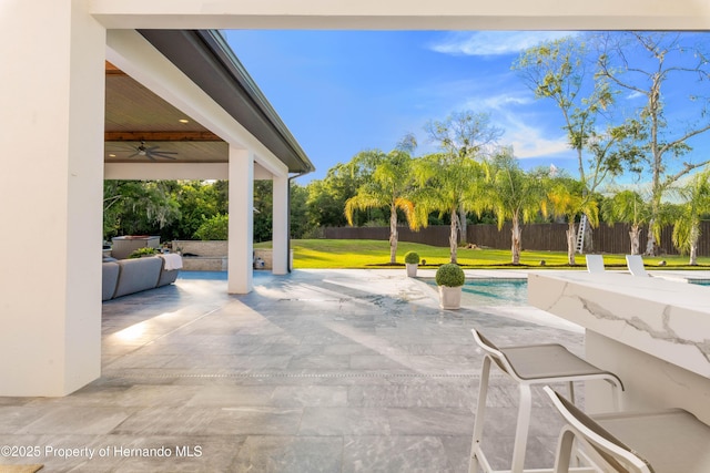 view of patio with ceiling fan, fence, and a fenced in pool