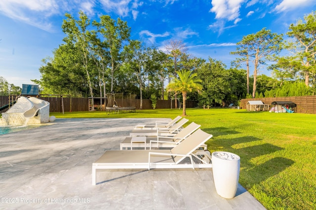 view of yard featuring a trampoline, a fenced backyard, and a patio