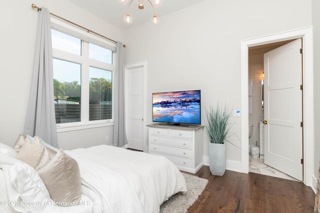 bedroom featuring baseboards, wood finished floors, and an inviting chandelier