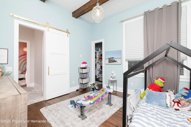 bedroom featuring a barn door, beam ceiling, baseboards, and wood finished floors