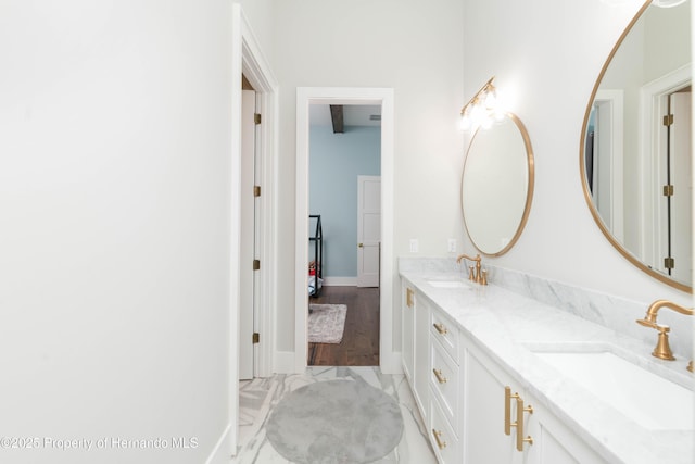 full bath with double vanity, a sink, and baseboards