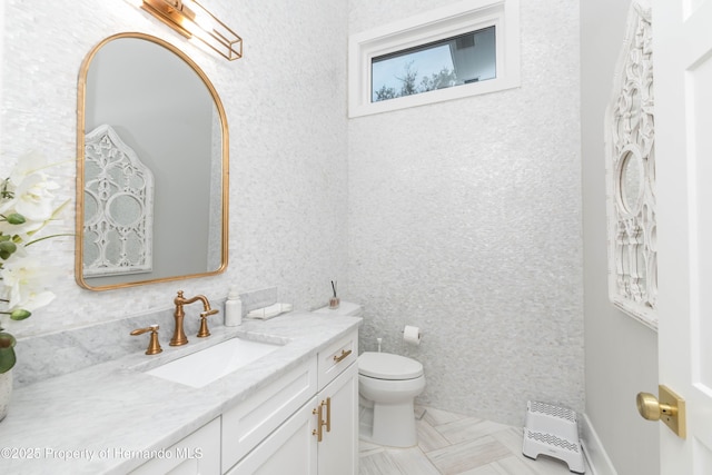 bathroom featuring vanity, toilet, and wallpapered walls