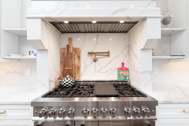 kitchen featuring extractor fan, high end stove, white cabinetry, backsplash, and open shelves