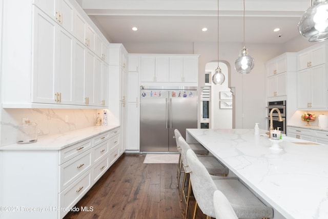 kitchen with stainless steel appliances, white cabinets, backsplash, and a kitchen bar