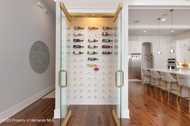 wine room with visible vents, baseboards, and dark wood finished floors