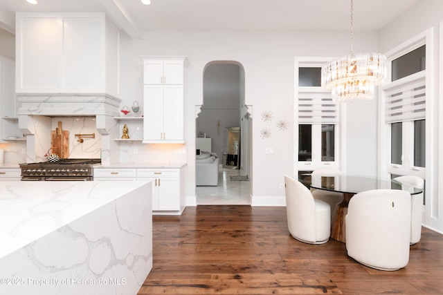 kitchen with tasteful backsplash, dark wood-type flooring, stainless steel stove, and white cabinetry