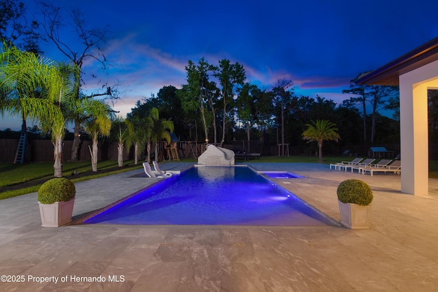 pool at dusk with a fenced in pool, a fenced backyard, and a patio