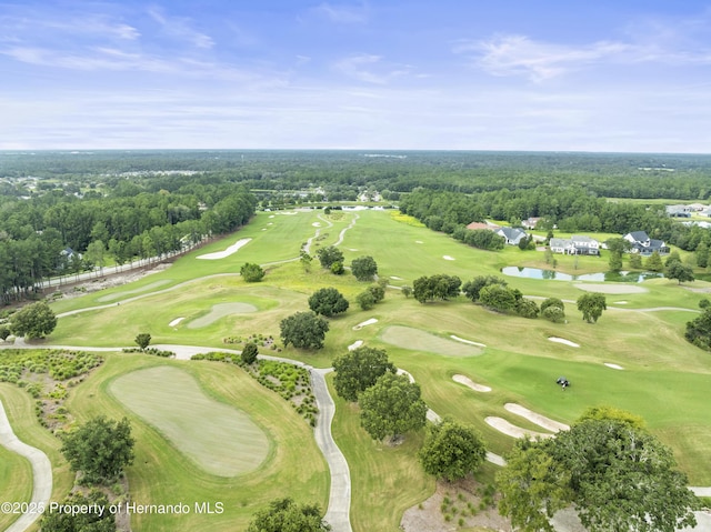 drone / aerial view featuring view of golf course and a view of trees