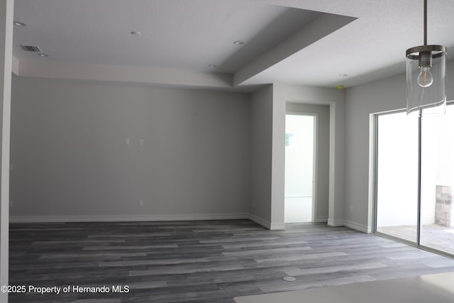 spare room featuring baseboards, visible vents, and wood finished floors
