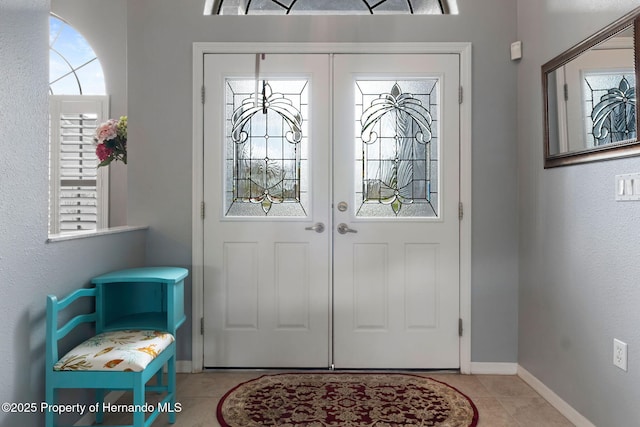 entrance foyer with tile patterned flooring, a wealth of natural light, and french doors