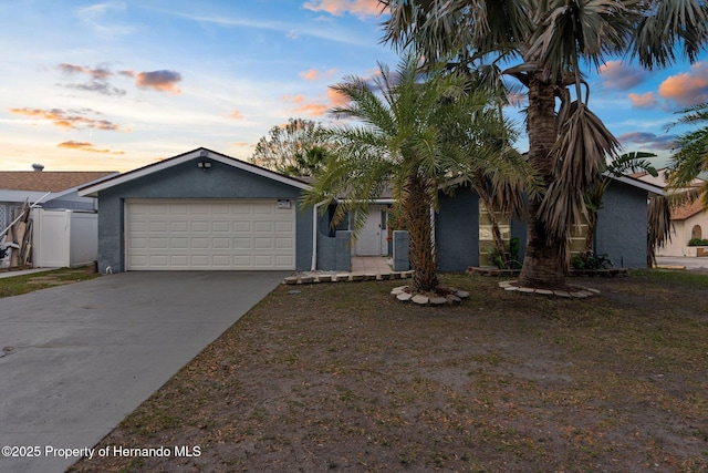 view of front of home featuring fence, central air condition unit, stucco siding, a garage, and driveway