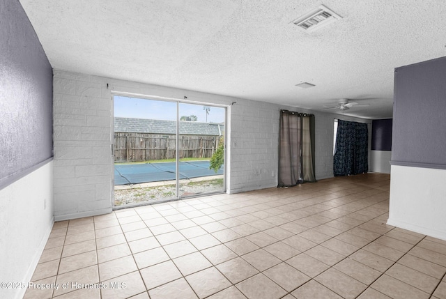 tiled empty room featuring visible vents, a textured ceiling, ceiling fan, and a textured wall