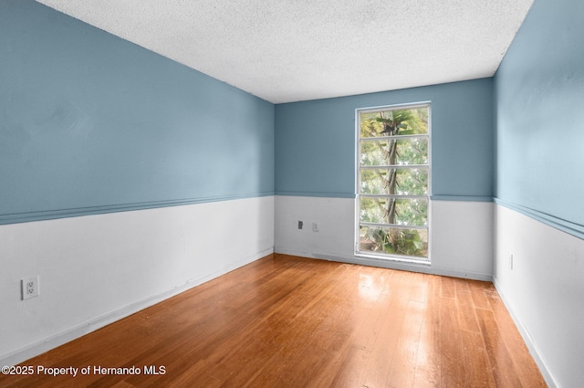 empty room featuring plenty of natural light, wood finished floors, and a textured ceiling