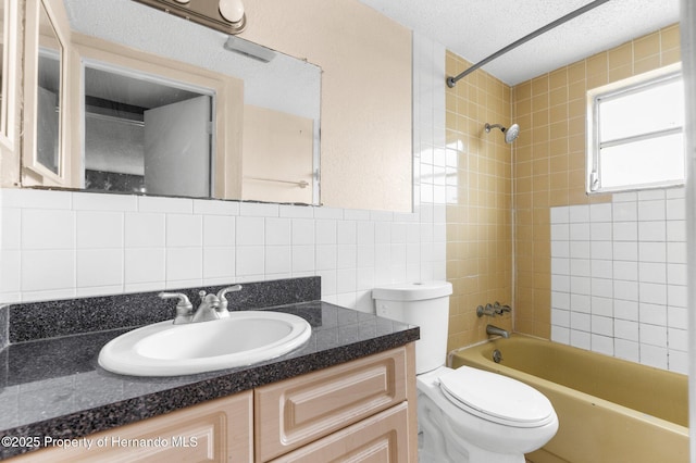 bathroom with tile walls, toilet, vanity, bathtub / shower combination, and a textured ceiling