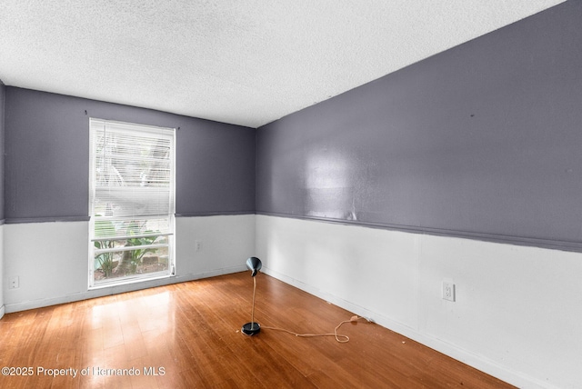 spare room featuring a textured ceiling and wood finished floors