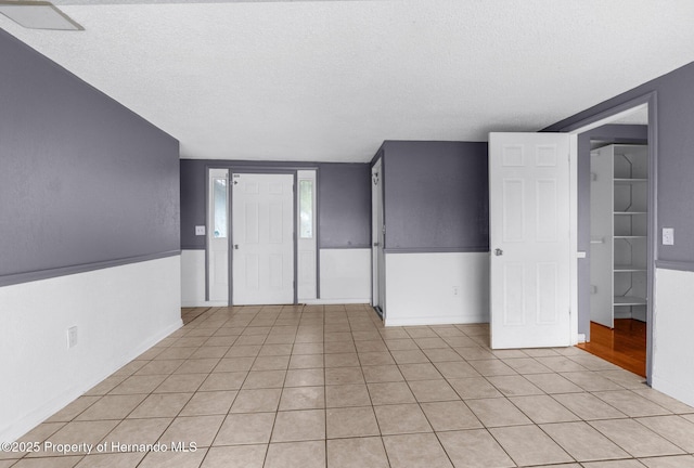 empty room with light tile patterned floors and a textured ceiling