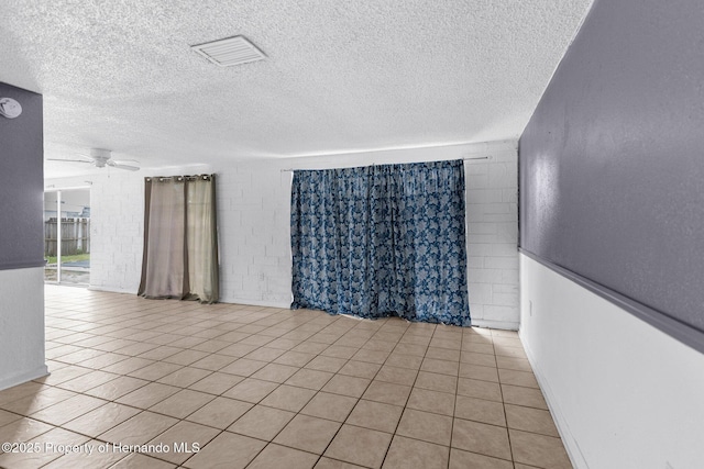 empty room featuring light tile patterned floors, visible vents, a textured ceiling, and ceiling fan