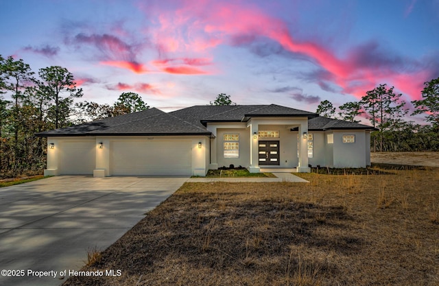 prairie-style home with a garage, driveway, a front lawn, and stucco siding