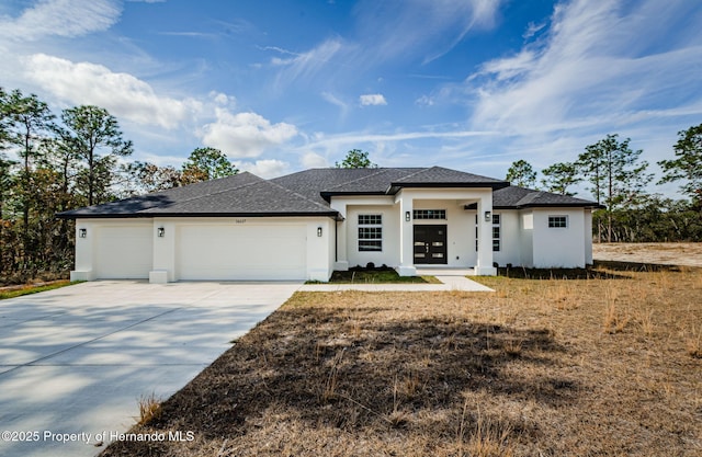 prairie-style house featuring an attached garage, concrete driveway, and stucco siding