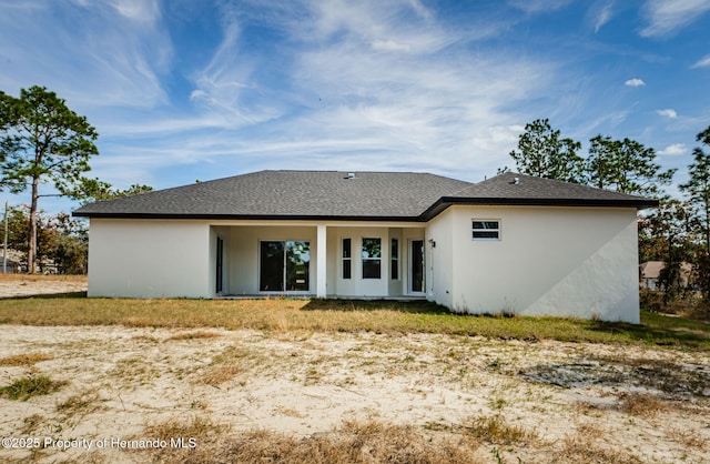 back of property with roof with shingles and stucco siding