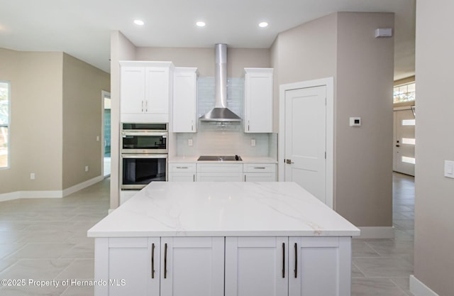 kitchen with stainless steel double oven, a healthy amount of sunlight, wall chimney range hood, and decorative backsplash