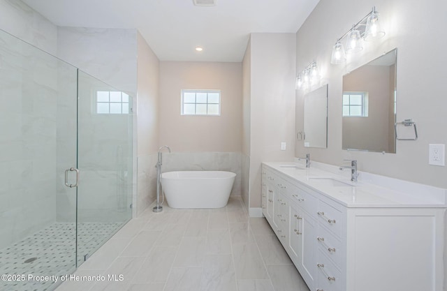 bathroom featuring a freestanding tub, a sink, a shower stall, and double vanity