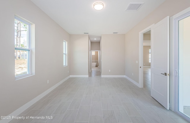 spare room featuring a healthy amount of sunlight, baseboards, and visible vents