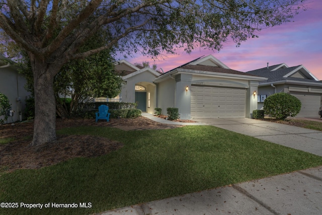 view of front of house with stucco siding, driveway, an attached garage, and a front yard