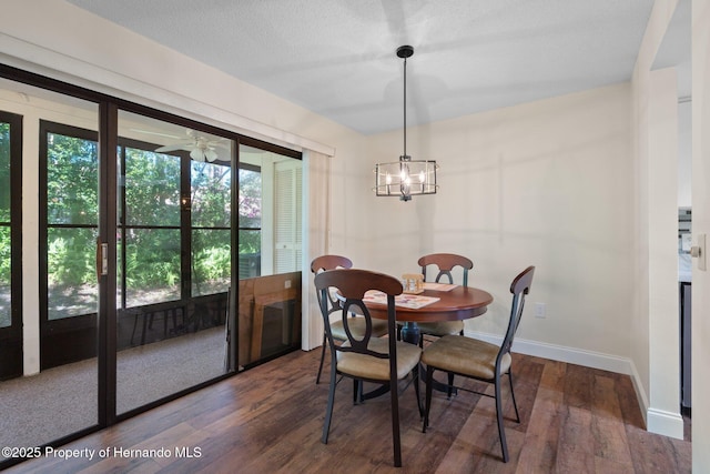 dining area featuring a textured ceiling, baseboards, a chandelier, and wood finished floors