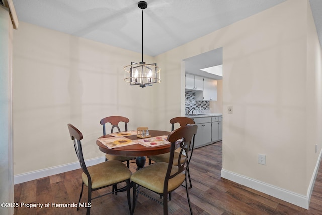 dining room with a notable chandelier, dark wood-style flooring, and baseboards