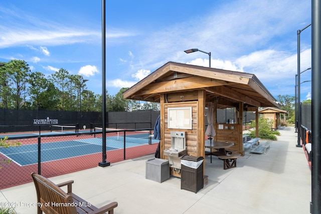 exterior space with a tennis court and fence