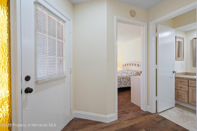 hallway featuring light wood finished floors and baseboards