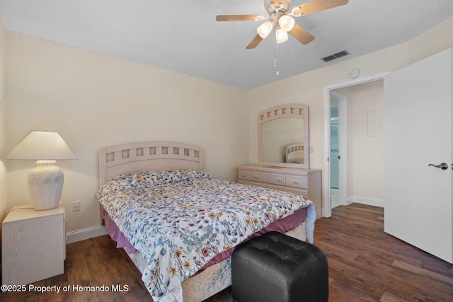 bedroom with a ceiling fan, visible vents, baseboards, and wood finished floors