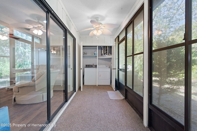 unfurnished sunroom featuring a healthy amount of sunlight, washing machine and dryer, and a ceiling fan