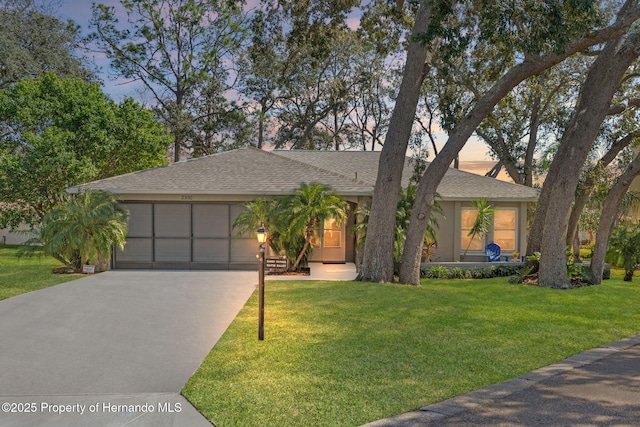 view of front of property with an attached garage, driveway, a front lawn, and stucco siding