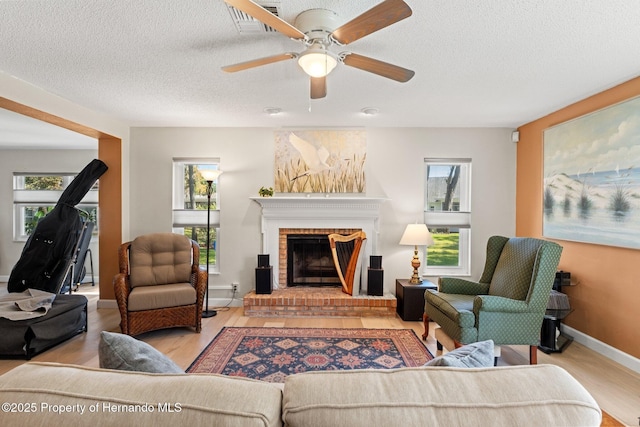 living room with a textured ceiling, a fireplace, wood finished floors, and baseboards