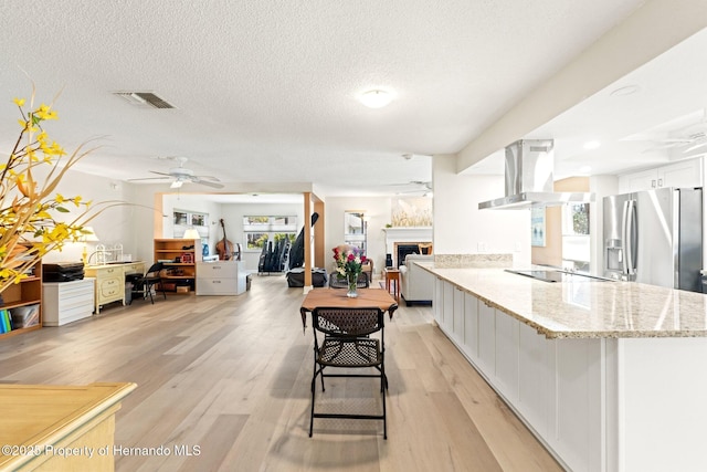 kitchen featuring light wood-style floors, a fireplace, island exhaust hood, and stainless steel refrigerator with ice dispenser