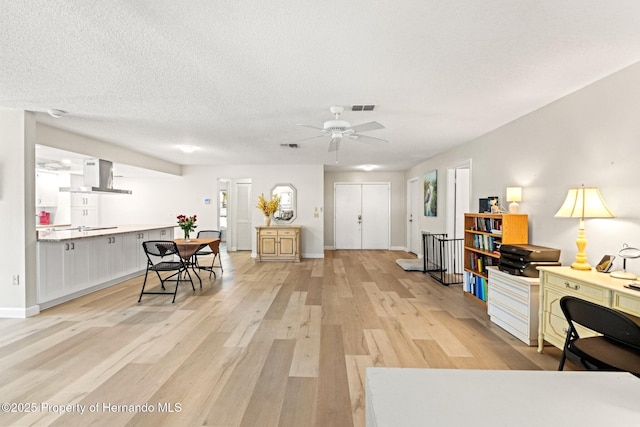 interior space with light wood-style floors, baseboards, visible vents, and a textured ceiling