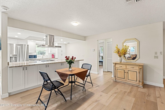 dining space featuring light wood-style floors, visible vents, and baseboards