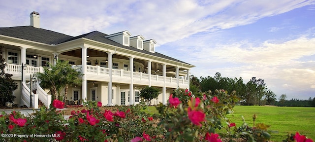 rear view of property with stairs, ceiling fan, and a lawn