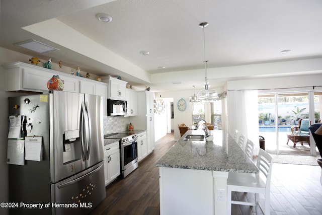 kitchen with a chandelier, stainless steel appliances, a sink, white cabinets, and a raised ceiling