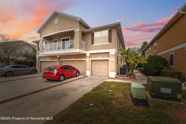 view of property featuring stucco siding, cooling unit, concrete driveway, and an attached garage