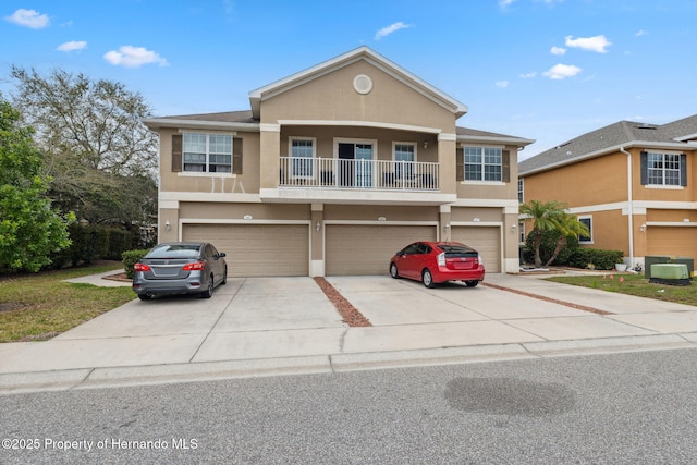 view of front facade featuring concrete driveway, a balcony, an attached garage, and stucco siding