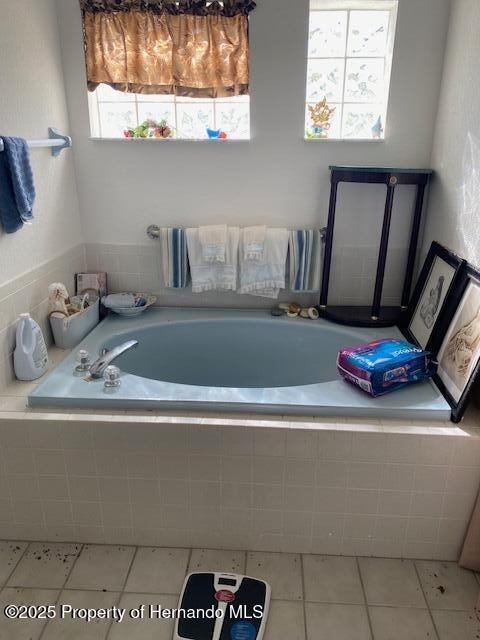 bathroom with a garden tub and tile patterned floors